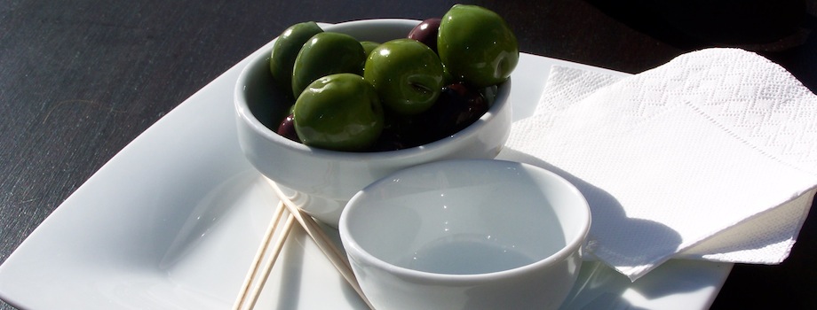Bowl of fresh green olives on a white plate